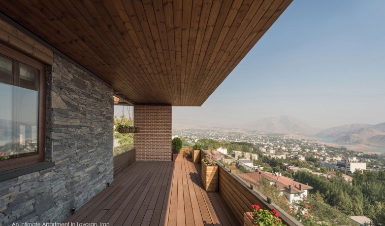 Wide terrace view across Lavasan town and the surrounding mountains, with wooden ceiling and stone wall
