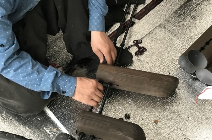 صنعتگری در حال مونتاژ یک قطعه از نما ـــ هر میخ به صورت دستی بر میله فلزی نشانده می‌شود.