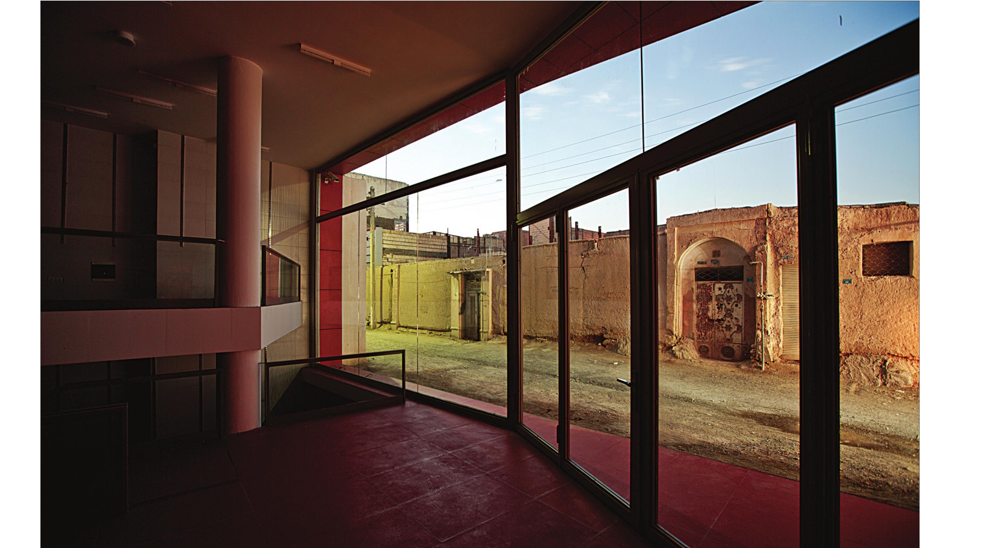 Interior with glass frame looking out to the historic mud-brick house across the alley