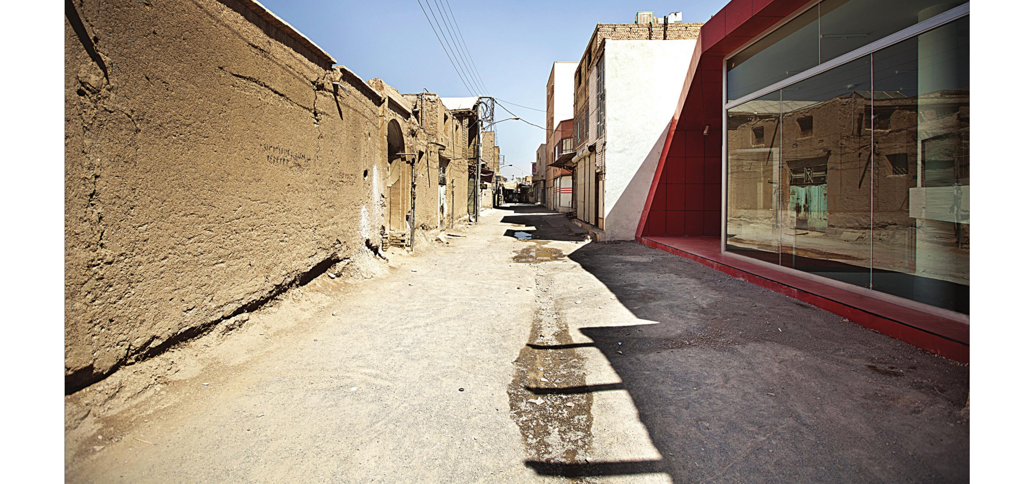 Street alley with the historic mud-brick wall on the left and red shop facade on the right