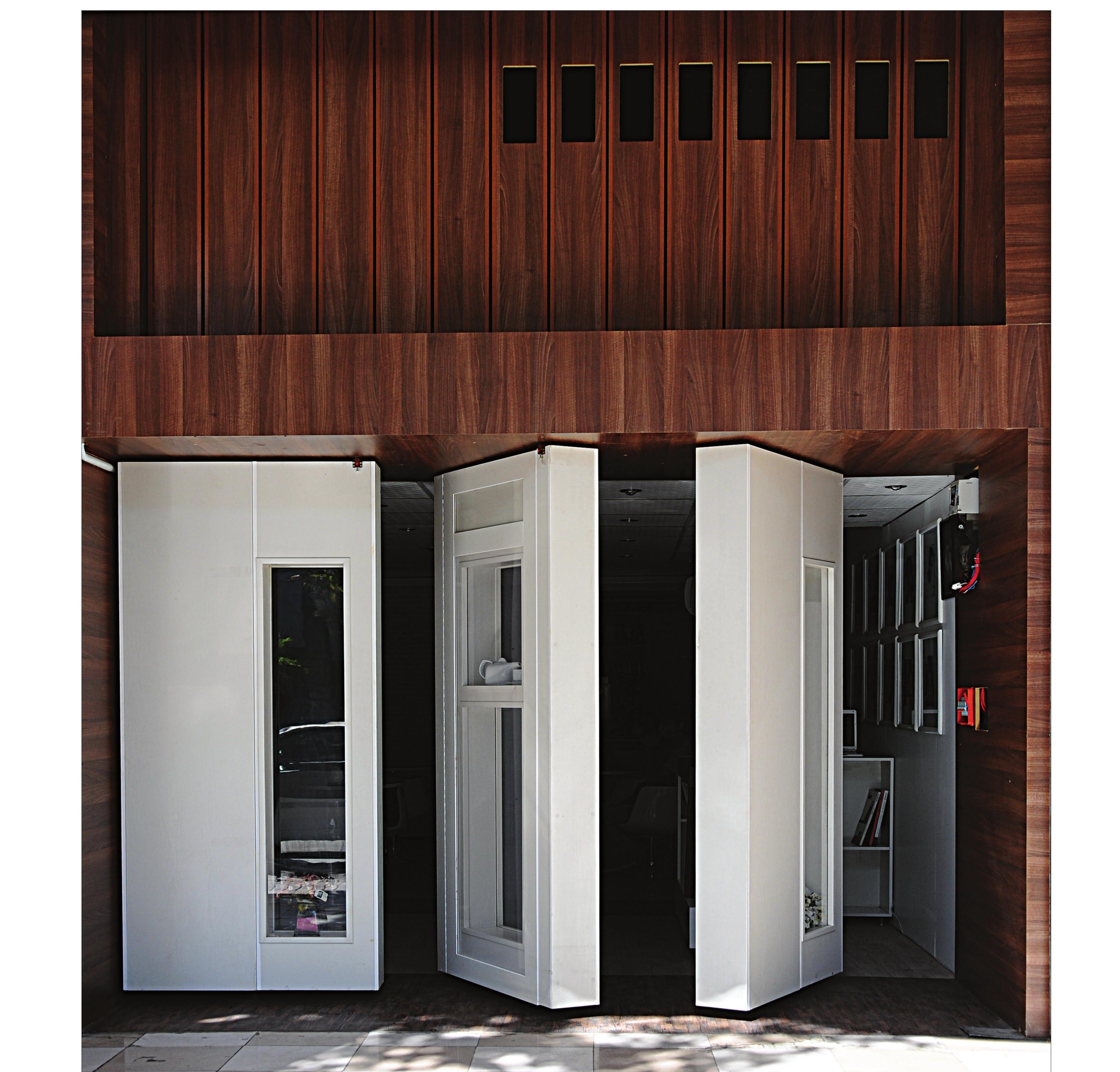 Full wood-clad two-storey facade with rotating doors below and ventilation slots above
