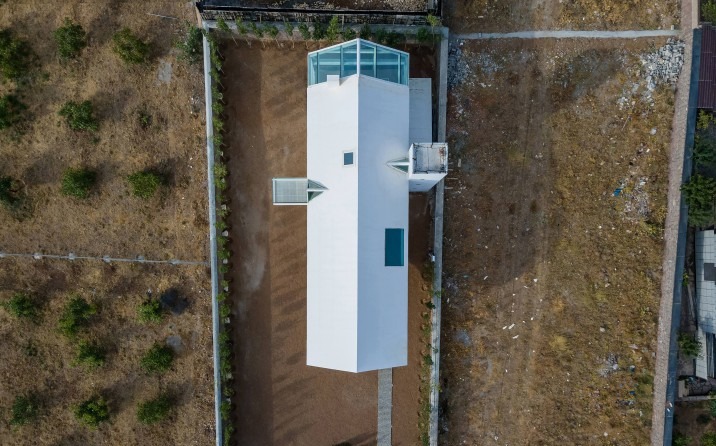 Top-down aerial of the white gabled volume with a central skylight pool