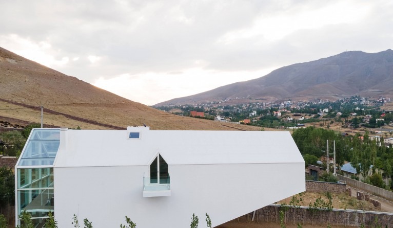 Distant view showing the rooftop greenhouse and skylight against the surrounding village and mountains