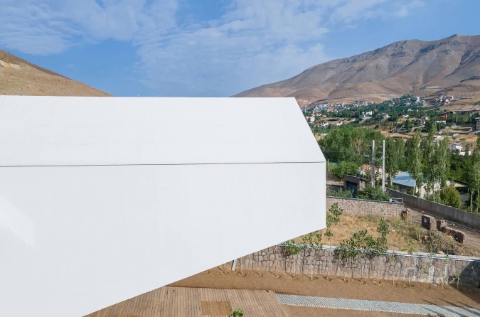 Underside view of the cantilevered north volume rising above the stone retaining wall
