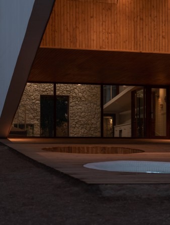 Twilight view from beneath the cantilever showing the sunken patio with stone wall and jacuzzi
