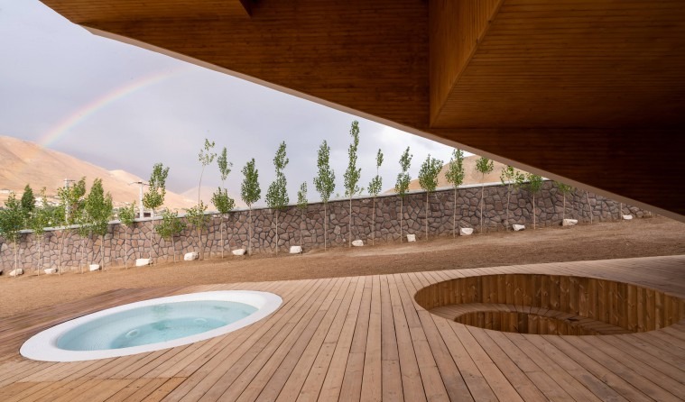 Wood-deck patio with jacuzzi under a rainbow with the mountains in the background