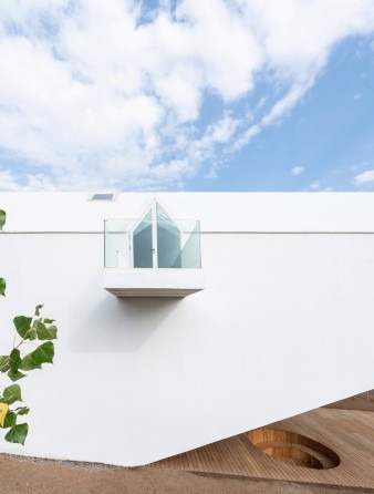 White exterior wall with skylight box rising from the roof and timber screen visible at the base