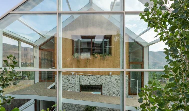 Greenhouse interior with bamboo planter wall, indoor garden and stone fireplace