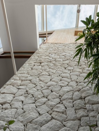 Stone-paved interior corridor under a glazed roof with planting on either side