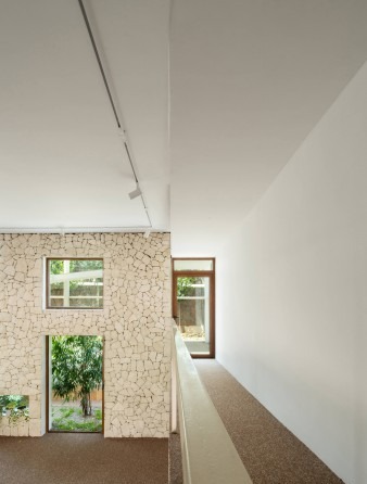 Stone-walled bedroom corridor with two windows looking onto the indoor garden and an exit door
