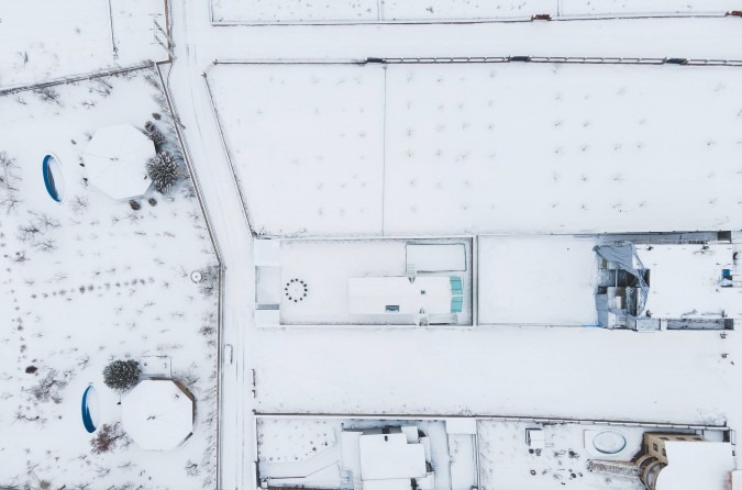 Top-down aerial in snow showing the rooftop skylight and surrounding landscape