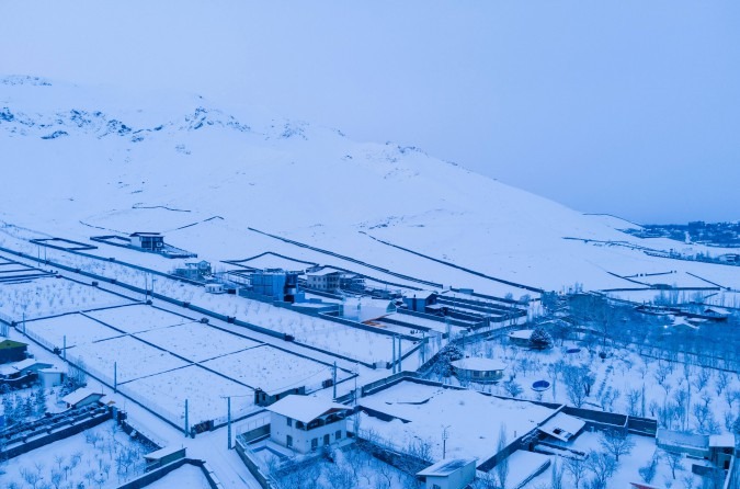 Distant snow view with the snow-covered foothills of Mount Damavand rising behind the village