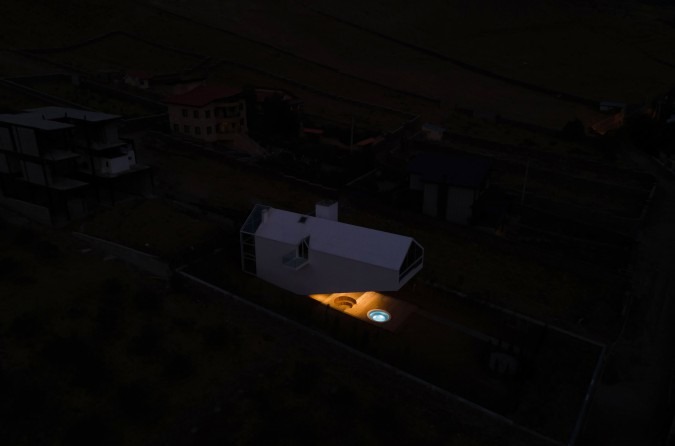 Distant night view of the small lit cantilever in the dark snowy plain