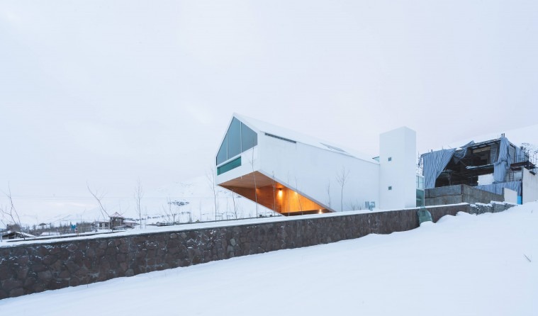 Snow exterior with the cantilever projecting over the stone retaining wall and the lit underside