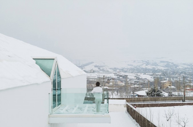 Snow balcony with figure leaning on the glass railing looking out over the snowy village