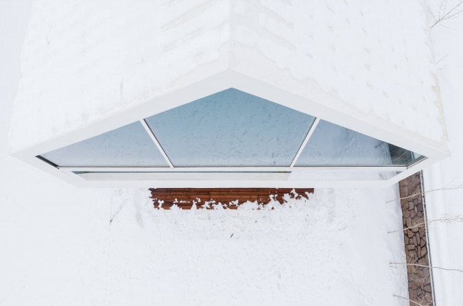 Top-down view of the skylight rimmed with snow and warm wood frame visible below