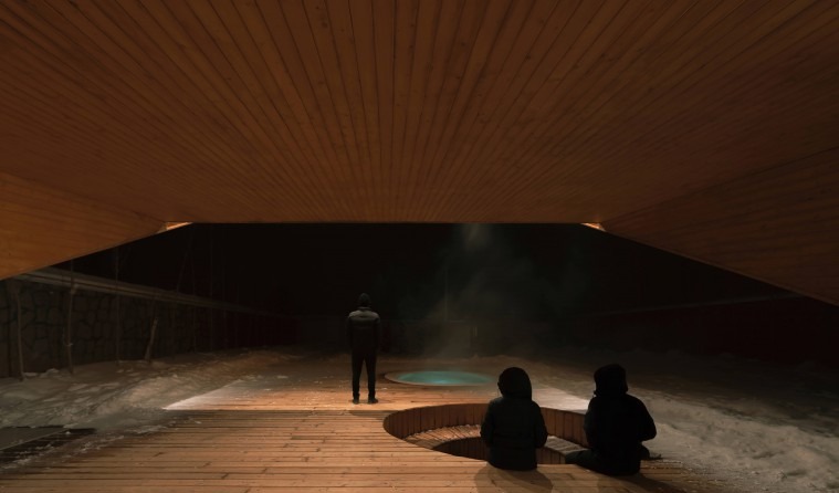 Snow night patio with three figures gathered around the lit jacuzzi under the wood-clad cantilever