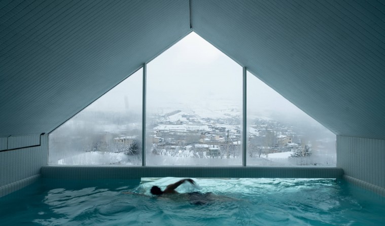 Indoor pool with the triangular winter view through the gable window and a swimmer crossing the lane