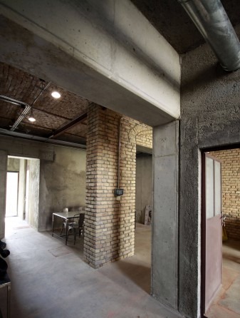 Interior of Farsh Film Studio with raw concrete beams and salvaged brick walls forming the renovated industrial-feeling space