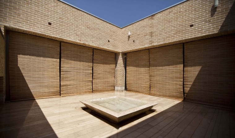 Brick-walled courtyard with bamboo screens and a low reflecting pool