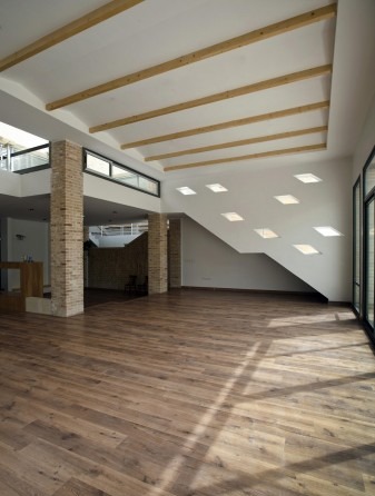 Open living room with skylights and exposed wooden beams over wood floor