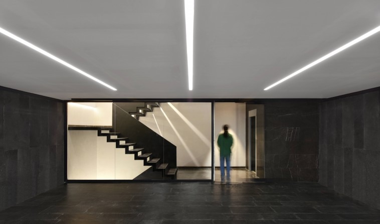 Lobby interior of Kar-Khaneh with a black stair and continuous LED-strip ceiling
