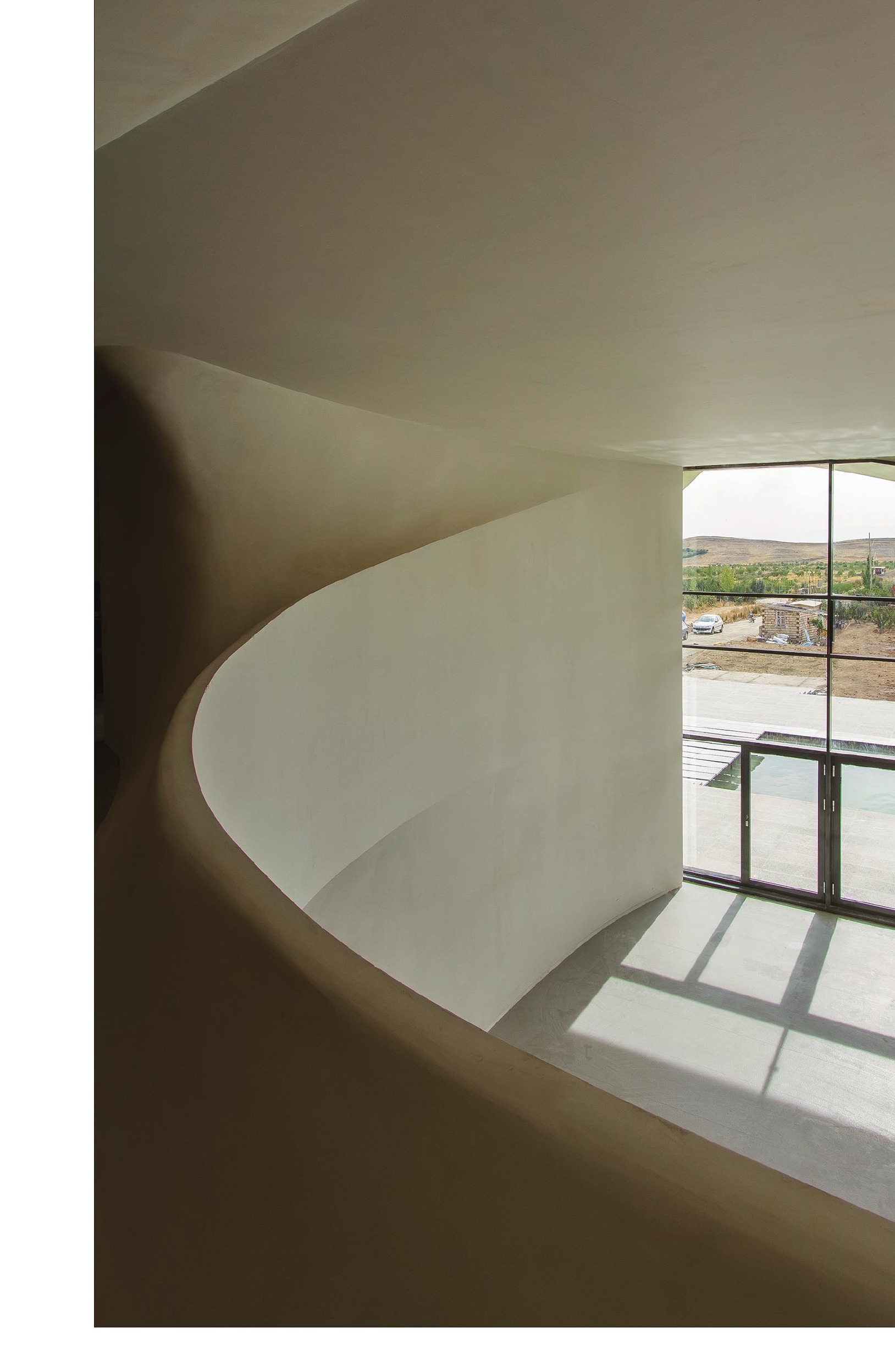 Interior double-height curved hall with balcony overlooking a courtyard pool