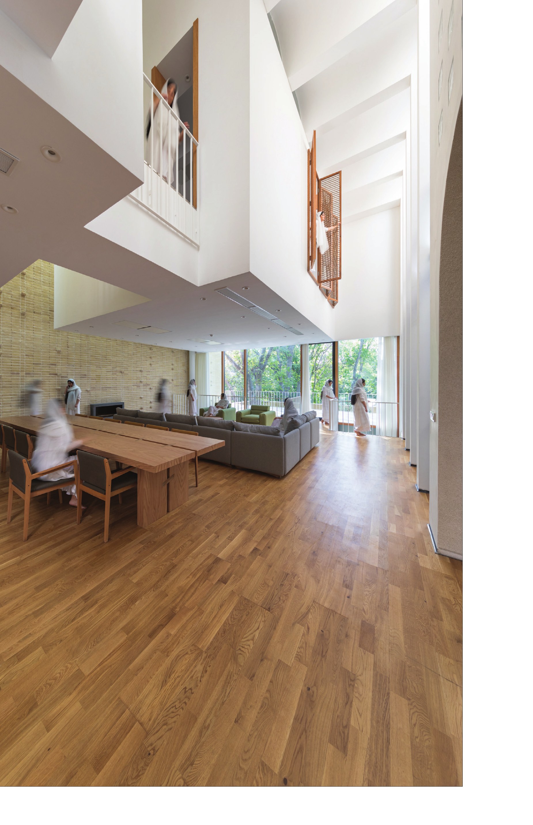 Double-height living and dining hall against the brick wall
