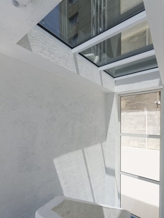A long perspective through Nabshi Gallery rooms with smooth blue floors and white walls broken by tall doors