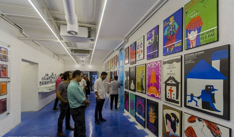 A wide colourful poster exhibition at Nabshi Gallery — visitors looking at illustrated theatre posters mounted in a long line