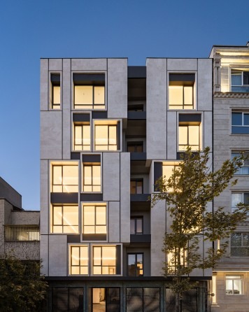 Niloofar 22 facade at dusk with interior lights showing through the rotated box openings