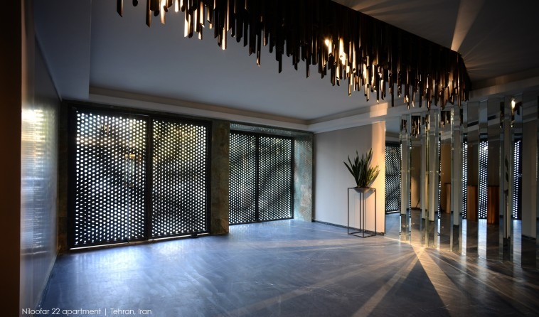 Lobby of Niloofar 22 with a sculptural ceiling of vertical brass elements above perforated screens