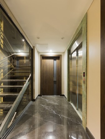 Stairwell of Niloofar 22 with glass balustrade and a green stone elevator surround