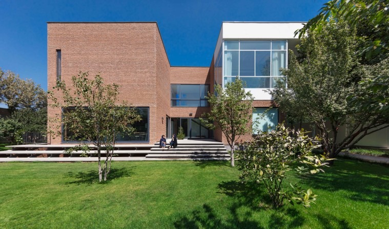 Safadasht Dual courtyard view — wood-trim glass walls with brick walls behind, connected by a planter and pool