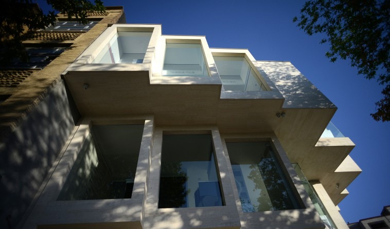Looking up at the new facade — three stories of stacked travertine-and-glass cubic display boxes