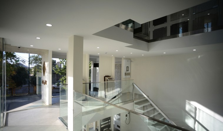 Interior of the tile showroom: a bright open ground floor with a transparent staircase opening up the vertical view between floors