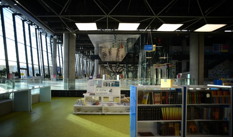 Tehran Book Garden interior — a long high gallery linking exhibition halls with bookshops below and a roof skylight