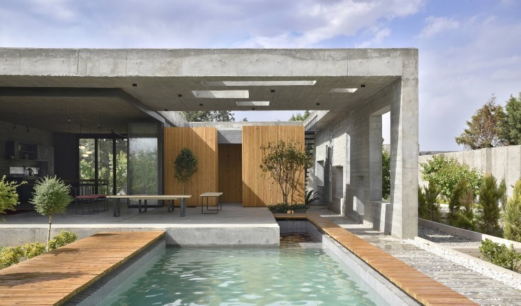 View from the pool deck looking back toward the wooden private boxes: skylights perforate the heavy ceiling above the se