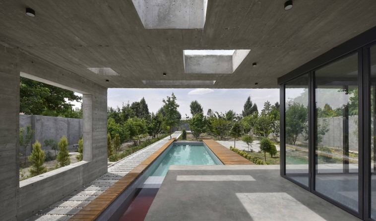 From beneath the slab outward: skylight cutouts puncture the concrete ceiling and frame an open view of the orchard, the