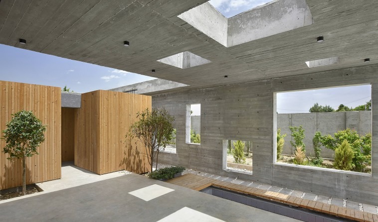 The semi-open central court: wood-clad service boxes face the bare board-formed concrete of the outer shell; cube-cut wi