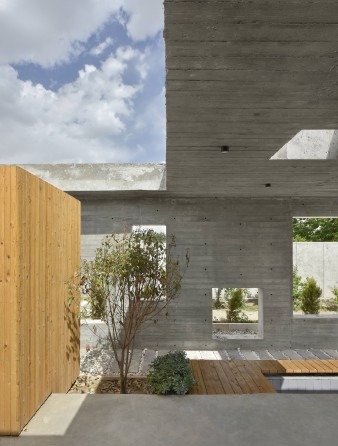 Detail of the board-formed concrete wall punched with three openings: the timber-clad private box pushes forward from th