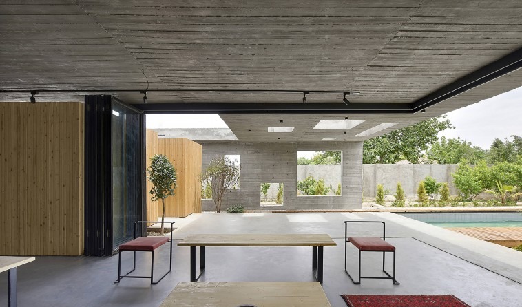 Looking from the living space toward the semi-open court: the retractable glass leaves only a thin black mullion line be