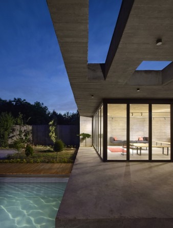 The same view at twilight: the living space glows warm through the glass, while the pool catches the last of the sky and