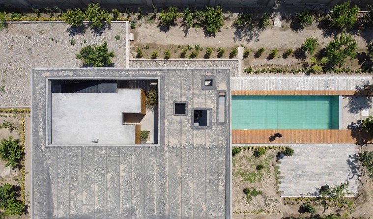 Aerial view: the sunken roof court above the wood-clad volumes reads as a stepped void at the cube's centre, while the t