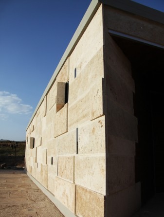 Side facade of the chapel with sharp-cut travertine and aperture windows