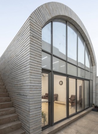Close exterior view of the arched glass-fronted vault entry seen from the side courtyard with rising stair