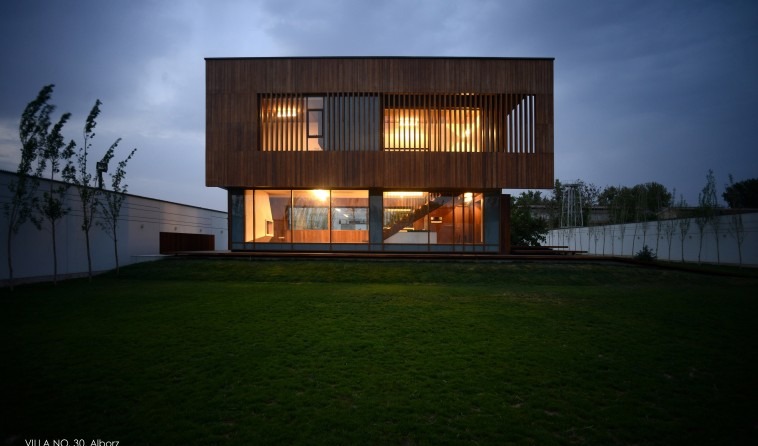 Villa No. 30 from the pool side: the wooden volume with a long horizontal mirror-glass opening reflects the pool