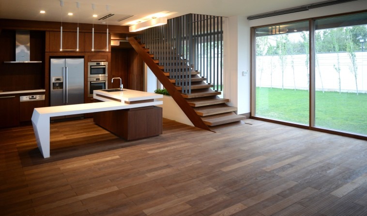Villa No. 30 interior — a long living-dining space with the kitchen beyond and a continuous wood floor extending out